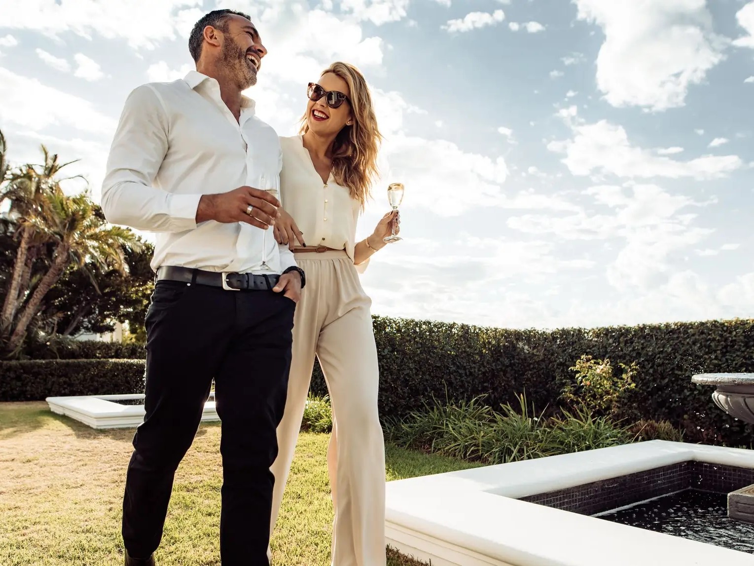 Couple walking together with wine in the lawn of their house